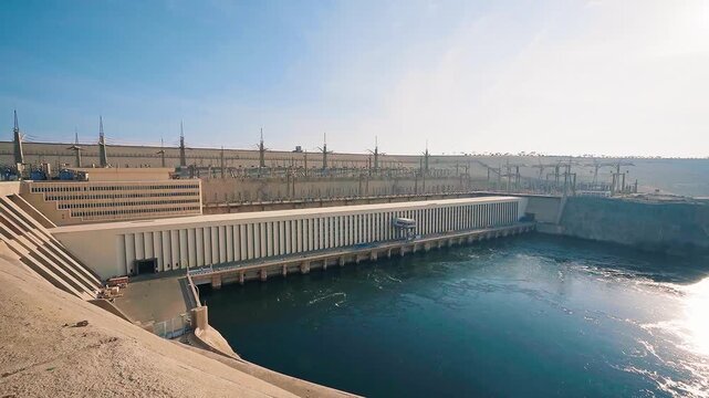 High Aswan Dam in Aswan, Egypt; Wide high angle shot of water spilling into emerald green lake from the walls of generating station.View of power plant of the Aswan High Dam