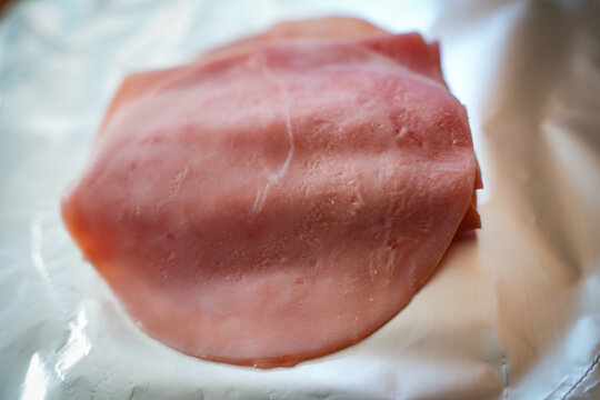 Sliced cooked ham arranged neatly as isolated deli meat on white background