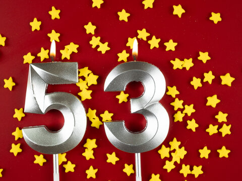 Number 53 silver celebration birthday candle on red with golden stars background. Fifty-three years birthday. celebrating anniversary and birthday