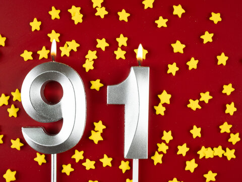 Number 91 silver celebration birthday candle on red with golden stars background. Ninety-one years birthday. celebrating anniversary and birthday