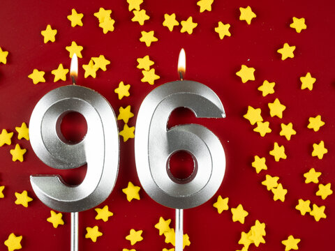 Number 96 silver celebration birthday candle on red with golden stars background. Ninety-six years birthday. celebrating anniversary and birthday