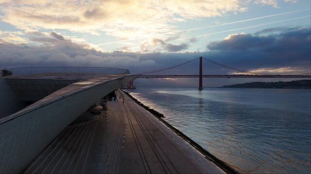 Aerial rise of MAAT museum and Tagus river waterfront with Lisbon coastline at sunrise. Lisbon, Portugal