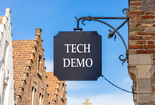 Tech demo symbol. Concept word Tech demo on beautiful black sign on street in Brugge. Beautiful blue sky and buildings background. Business tech demo concept. Copy space.