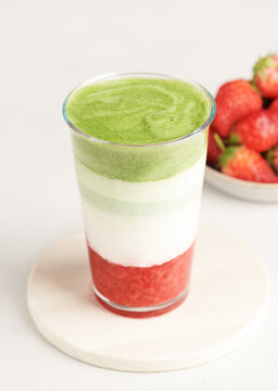 Strawberry matcha latte in glass with milk on minimal background, selective focus