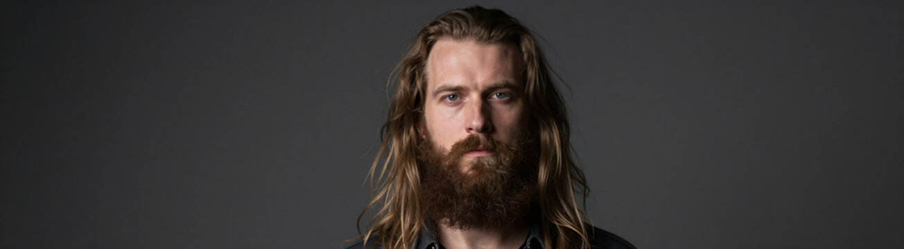 shot bearded man unkempt long hair beard dimly lit dark grey background soft focus