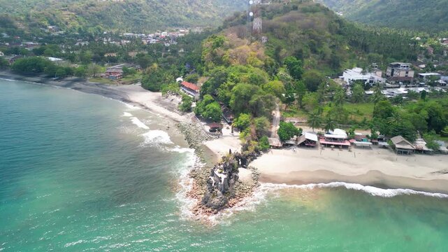 Aerial drone view of Pura Batu Bolong Hindu temple Lombok Indonesia perched on rock formation with ocean waves below