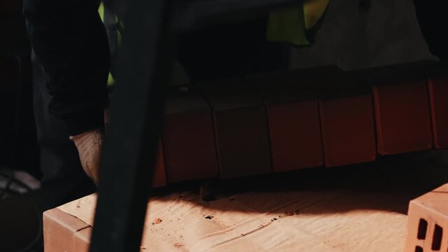Worker picking up brick from stack at construction site close up