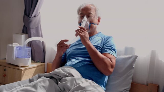 Senior man using oxygen mask with nebulizer in bedroom during home care respiratory therapy, elderly patient resting in bed for breathing support, calm recovery mood with medical device