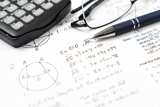 Mathematics geometry handwritten notes and circle diagrams paired with a scientific calculator and a ballpoint pen for college education