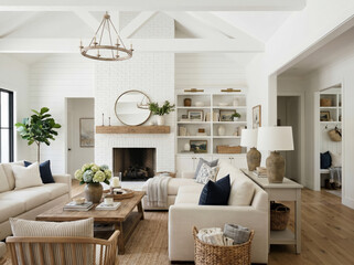 Fototapeta premium A white modern farmhouse living room with shiplap walls and beams on the high ceilings and cozy furniture sits around a white fireplace.