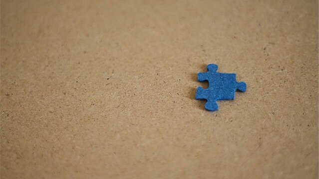 Single Blue Puzzle Piece on Brown Background.