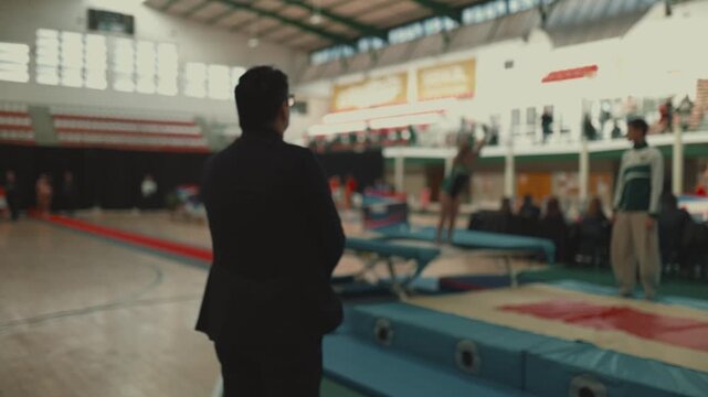 Judge watching young gymnast perform trampoline routine