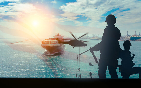 Dramatic composite image of armed military soldiers in silhouette and a helicopter with rappelling troops guarding a large cargo container ship at sea. 