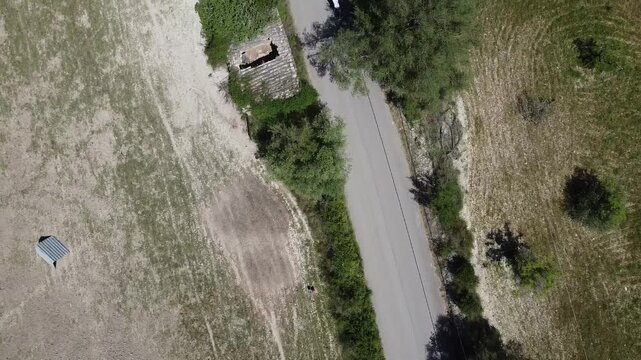 Aerial view of a large group of cyclists riding on a rural road in Mallorca during a bike race, Mediterranean landscape background.