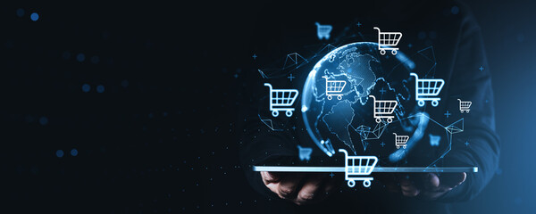 Global online shopping tech concept with glowing cart icons around digital world sphere emerging above tablet device in dark space. © ImageFlow