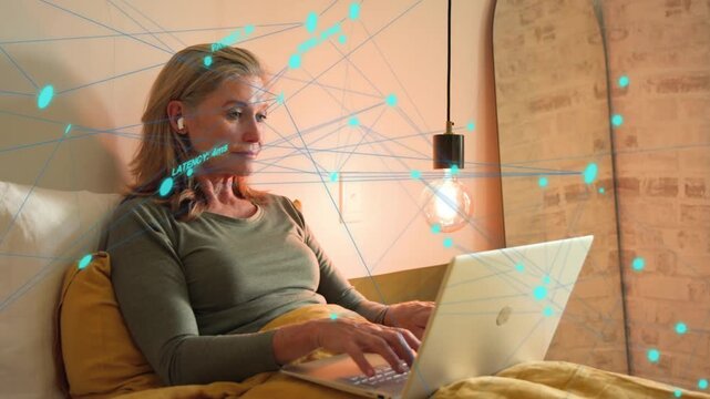 Mature woman typing on laptop, checking ping as network overlay radiates, closing laptop smiling