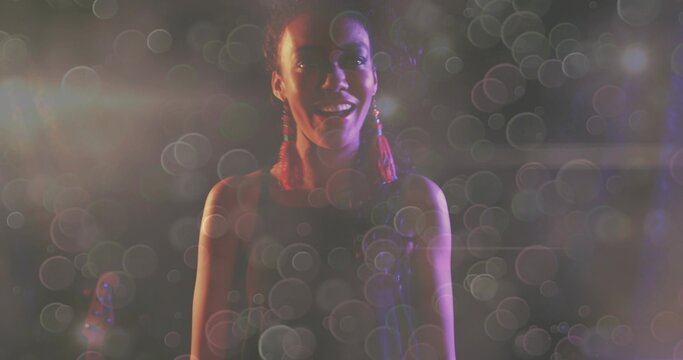 Singing singer center stage, wearing sleeveless top, red tassel earrings, mic, guitar, bokeh haze