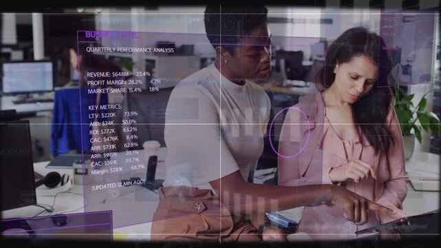 Two women tapping and scrolling tablet at desk, HUD showing quarterly business metrics for review