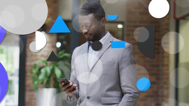 Man tapping smartphone in business lobby checking schedule while shapes animating and obscuring him