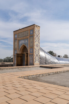 View of the entrance to the Ulugh Beg Observatory featuring intricate mosaic tilework and a curved roof structure in Samarkand, Samarqand Region, Uzbekistan.