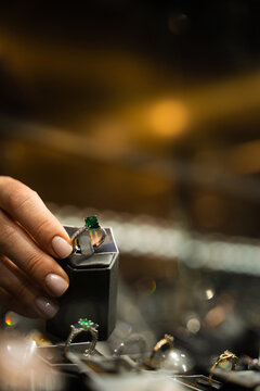 Customer selecting ring from jewelry display in retail store.