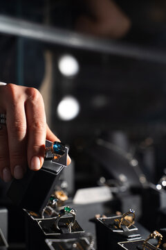 Buyer picking ring from jewelry display case in retail setting.