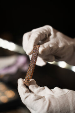 Jeweler inspects bracelet with protective gloves to preserve surface and quality.