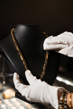 Jeweler polishing a gold necklace on a display bust.