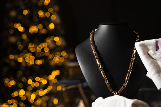 Expert jeweler cleaning a gold pendant necklace on a mannequin bust.