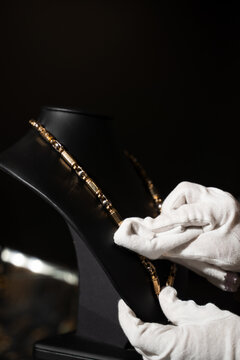 Jeweler polishing a gold necklace on a display bust.