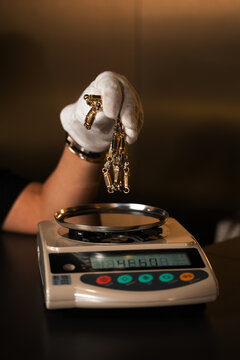 Jeweler weighing gold chain on precision scale to determine exact value.