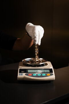 Close up of jeweler measuring gold chain weight on digital scale for valuation.