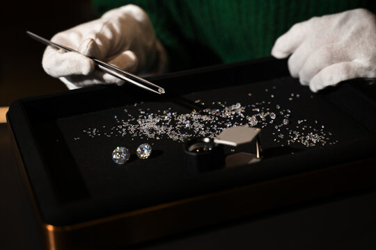 Gemologist holds a small diamond with tweezers for precise inspection and sorting.