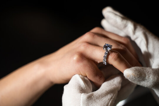 Close up of bride hand receiving engagement ring from jeweler in store.