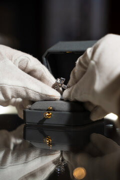 Close-up of jeweler in white gloves packaging ring into elegant box.
