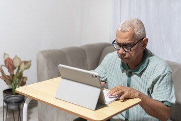 Fototapeta premium Routines senior man typing on tablet computer at home
