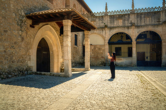 Woman capturing ancient architecture with her smartphone in a spanish cloister