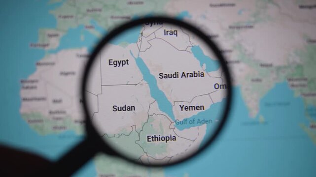 Magnifying glass over Saudi Arabia and Yemen map highlighting red sea tensions, Houthi activity, Iran influence and Strait of Hormuz trade routes shaping global security and energy supply risks