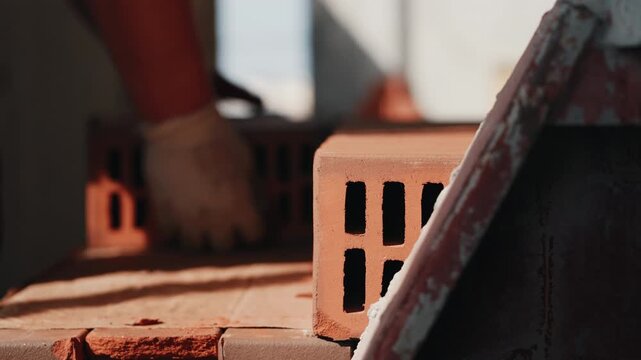 Stack of hollow bricks on construction site with worker in background close up