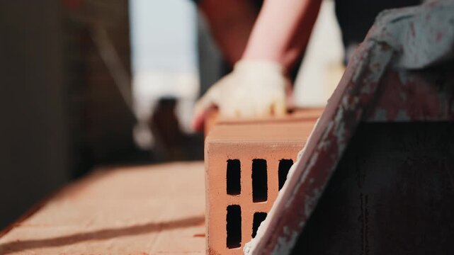 Worker carrying hollow bricks from stack at construction site close up