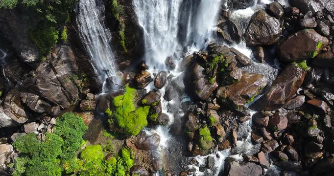 Cinematic aerial 4K footage of Veu da Noiva waterfall located in the Serra do Mar, Brazil. The scene showcases powerful cascading water flowing over rocky cliffs surrounded by dense tropical rainfores