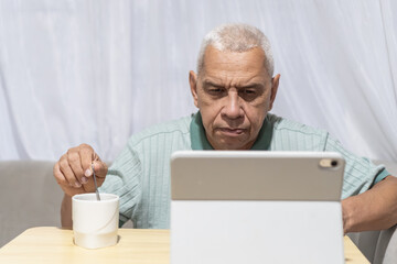 Fototapeta premium Routines senior man concentrating on tablet while drinking coffee