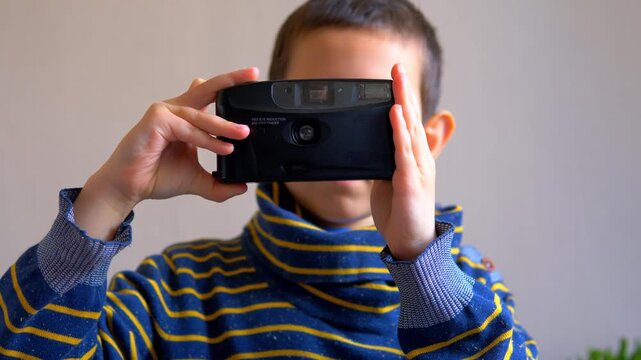 Child Taking Photo with Black Point-and-Shoot Film Camera, Young Photographer Pressing Shutter Button with Flash Firing