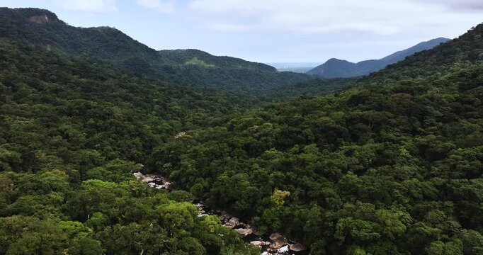 Cinematic aerial 4K footage of Veu da Noiva waterfall located in the Serra do Mar, Brazil. The scene showcases powerful cascading water flowing over rocky cliffs surrounded by dense tropical rainfores
