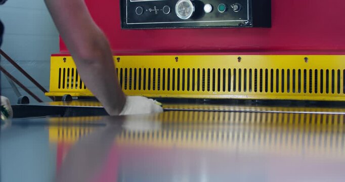Sheet metal positioned under guillotine shear blade in industrial workshop, preparation for cutting process