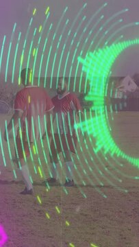 Vertical video: Soccer players redirecting air ball, keeping ball while neon rings sweeping pitch