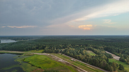 Fototapeta premium Aerial view of serene landscape showcasing sprawling forests, meandering rivers, and open fields. Soft sunset light creates a tranquil atmosphere, perfect for nature-related projects.