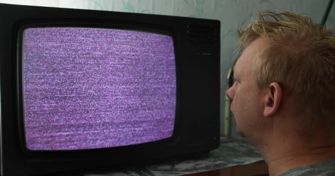 Person staring at CRT television with TV static on the screen. Screen hypnosis, media addiction, and visual fixation on analog noise