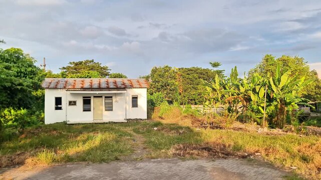 Abandoned White House Surrounded by Lush Nature in Rural Village