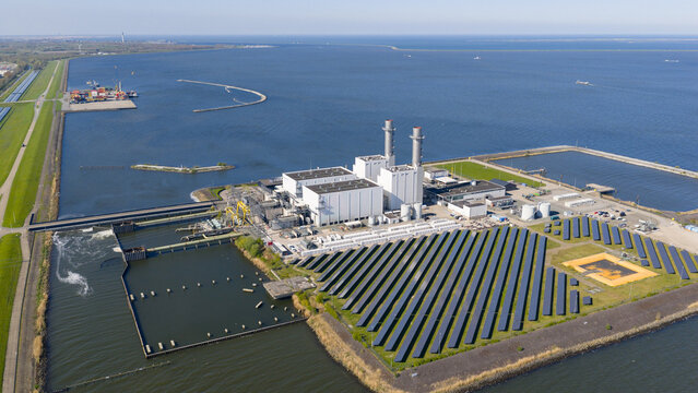 Lelystad, Netherlands - 21 April 2026: Aerial view of the Maxima plant power station and offshore wind turbines along the coast under a clear blue sky.